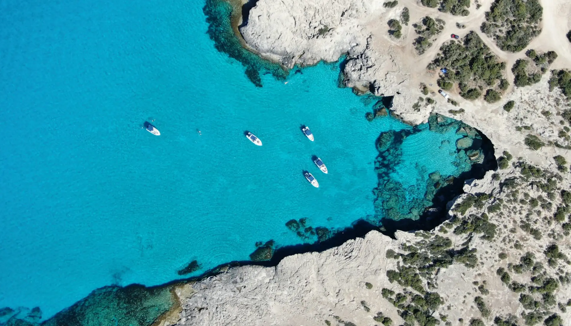 Aerial view of small boats anchored in the turquoise water of the Blue Lagoon near Paphos, Cyprus